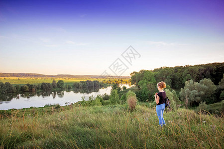 年轻女孩欣赏大自然的美丽夏季风景与河图片