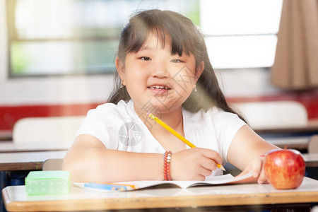 小学的亚洲女学生在课桌前快乐阳光从图片