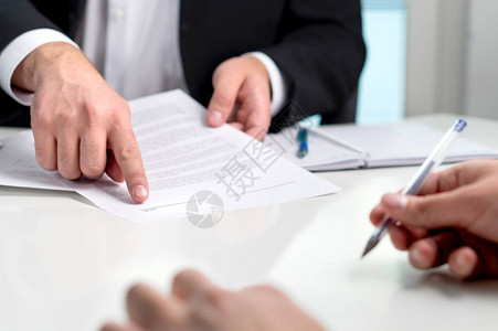 签订合同或协议银行家或律师在文件纸上向客户展示签名行与客户在办公室做交易的商人背景图片