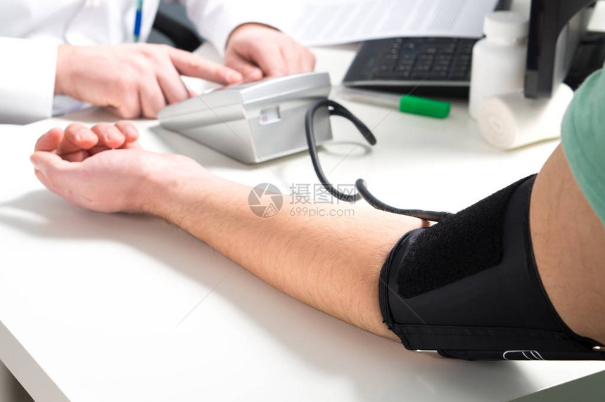 医生或护士用仪表和监测设备测量病人的血压图片