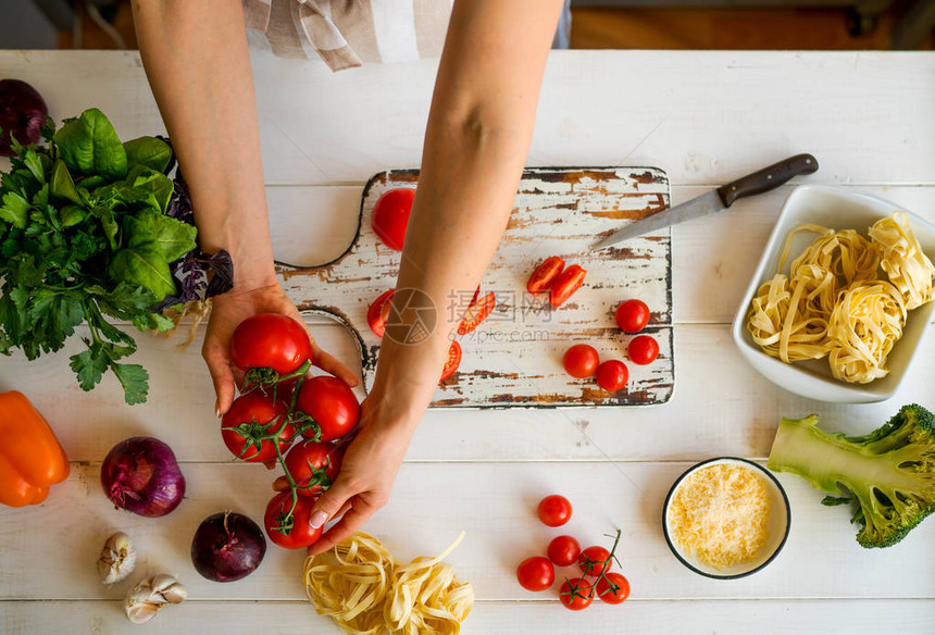 哄时间关闭了手拿着有机西红柿的照片年轻的wooman在厨房里准备食物制作美味沙拉的年轻女子健康的生活方式在家做饭图片