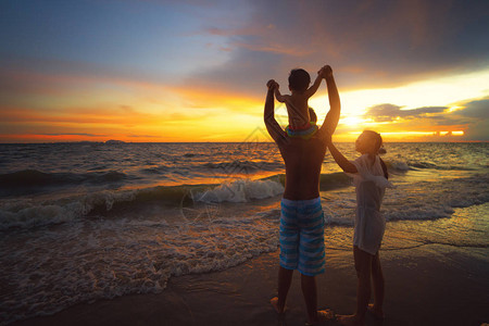 亚洲家庭的母亲父亲和婴儿在日落时分留在海滩上图片