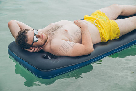 男人在海中游泳床垫上游泳图片