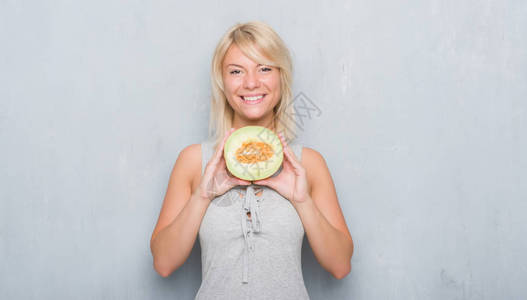 高加索成年女在灰墙上吃着哈密瓜图片