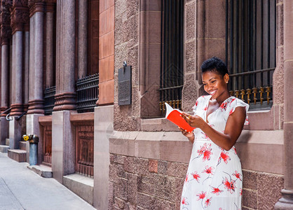 成功之路阅读的力量年轻漂亮的非洲裔美国女大学生站在纽约街上窗户的老式墙上背景图片