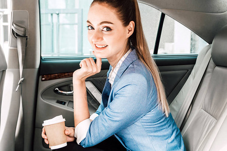 女商人在豪车后座端着一杯咖啡图片
