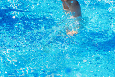 蓝色水池中水下的腿特写图片