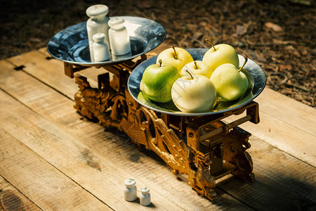 旧天平在木桌上涂的砝码和青苹果图片