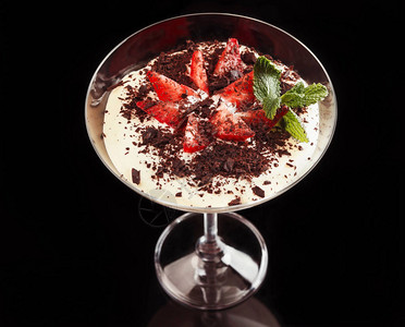 玻璃杯中的提拉米苏黑色背景中带可新鲜草莓和薄荷的意图片