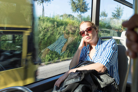 睡在车窗上的女人的肖像坐长途公交回家的图片