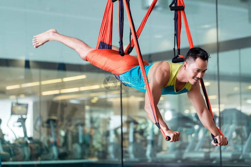 在配备现代设备的时尚健身俱乐部练习反重力瑜伽时图片
