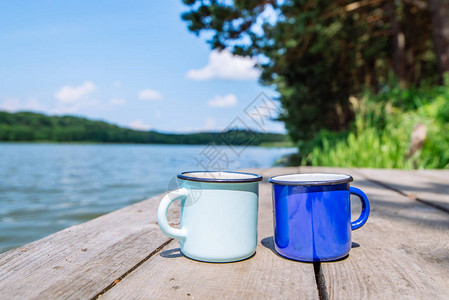 两杯装茶的金属杯子背景为河流图片