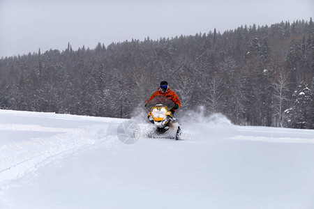 骑着雪地摩托的员在南乌拉尔山脉的冬季森林图片