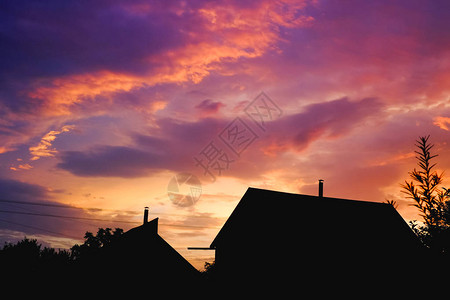 紫色夕阳下的房子和树的剪影图片