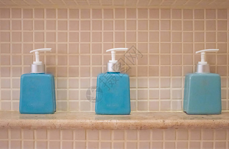 浴室架子上的液体肥皂和洗发水瓶背景图片