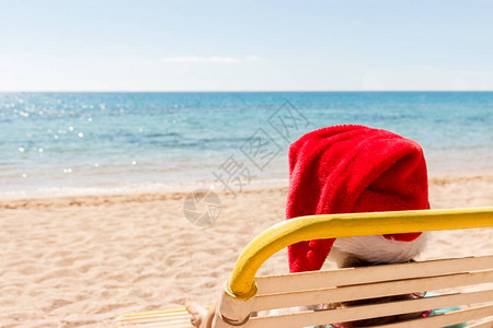 坐在圣诞老人帽子的沙滩阳光下的快乐女郎图片