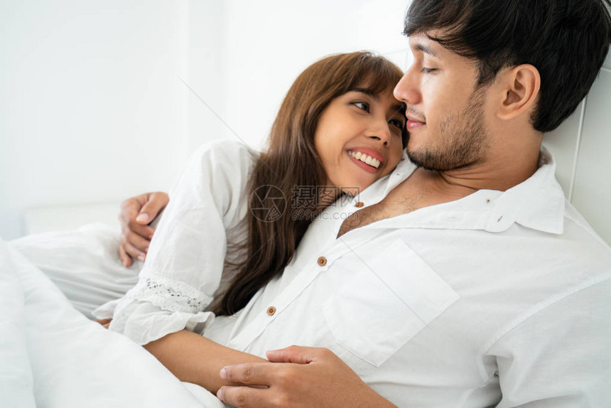 快乐的年轻夫妇在早上醒来后在家庭卧图片