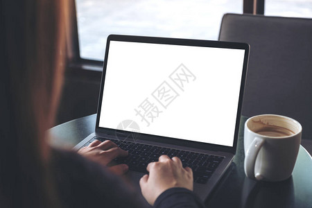 商业妇女使用笔记本电脑并用空白屏幕和咖啡杯在咖啡厅桌上图片