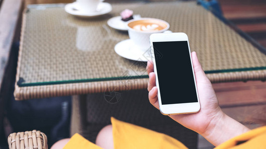 在咖啡馆中用黑屏空白的色手机拍摄女手握白色背景图片