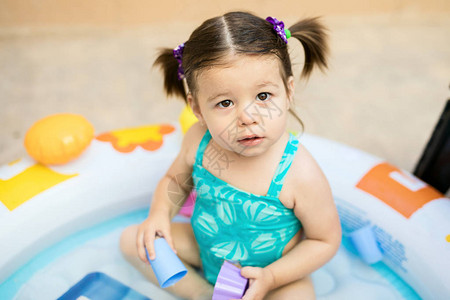 穿着泳衣的漂亮小女孩在后院一个充气池里玩水背景图片