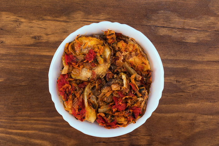 蔬菜开胃菜炸鱼环用西红柿洋葱和胡萝卜在白瓷碗里用木制背图片