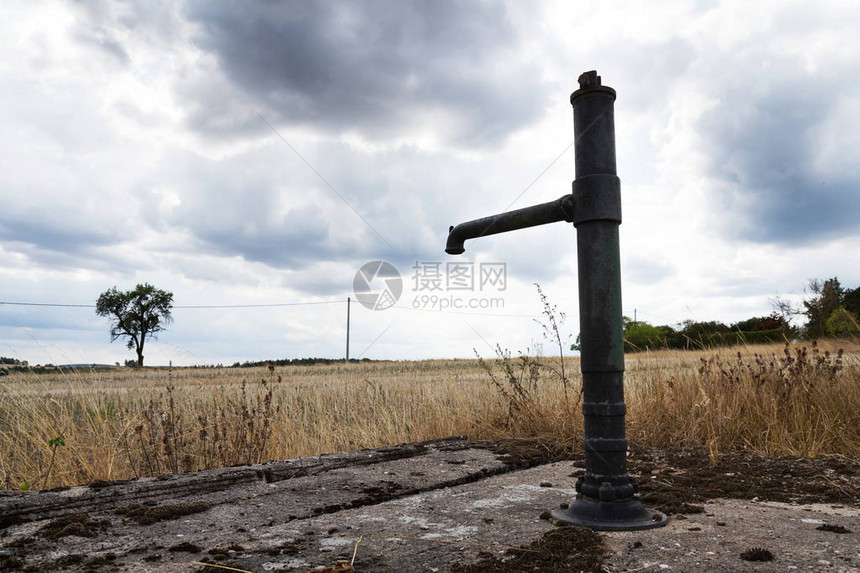 古老的生锈泵包括干土和黄草大云层背图片