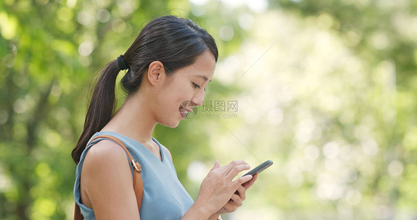 在绿色背景下使用手机的女人图片
