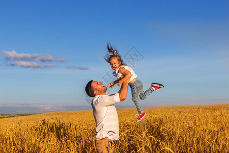 英俊的年轻男人一个快乐的父亲和女儿一起玩耍在温暖的夏日阳光下图片
