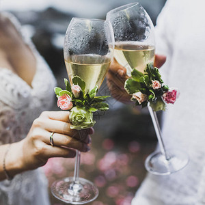 男人和女人手握着两杯香槟杯盛装鲜花图片