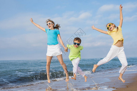 3个快乐的孩子白天在海滩上奔跑图片