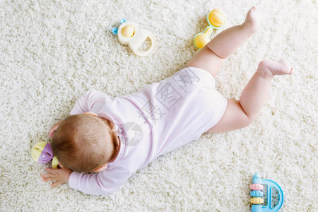 健康婴儿身体和腿的特写镜头与许多五颜六色的拨浪鼓玩具图片
