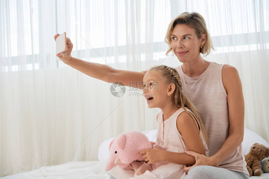 快乐的母亲和女儿在家中床上用手图片