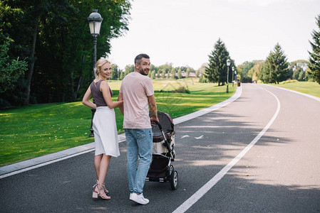 父母在公园的公路上随婴儿车行走图片