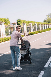 父亲在公园里推着婴儿车走路的背影图片
