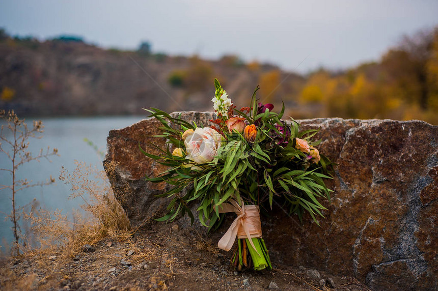 婚礼花新娘花束与山河背景附近的不同色调的玫瑰适用于杂志和网站文案空间时尚波西米亚风格花卉装饰企业花店和其他相关主图片