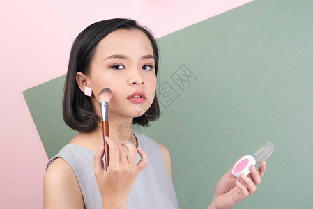 亚洲年轻女子在脸颊上涂抹腮红图片