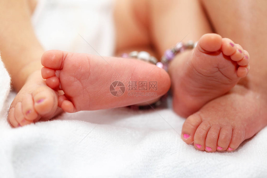 两名身着紫色和粉红脚趾指甲油的同型双生婴儿女婴脚足图片