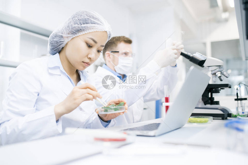 两位现代科学家在医学实验室研究时研究物质的侧视肖像图片
