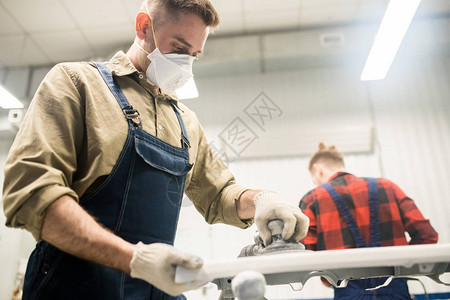 男汽车技师在修理车间用研磨工具进行保护面罩沙砂车细件和碾磨工具图片