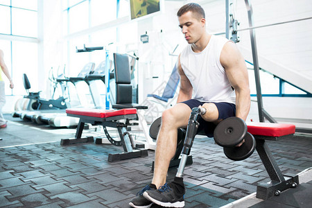 在健身房锻炼的肌肉男用哑铃锻炼图片