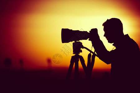 金色时光摄影男子用大长望远镜头拍摄背景图片