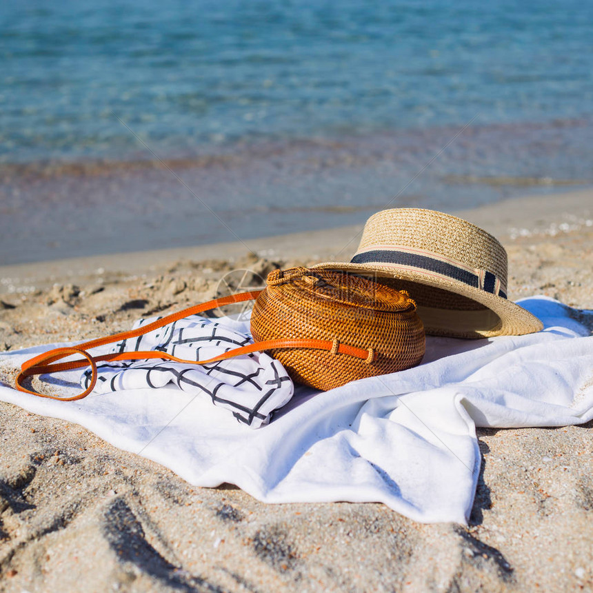 在帽子和其他配件旁边的沙滩上白色地板上的现代妇女圆形包装袋还有其他饰品图片