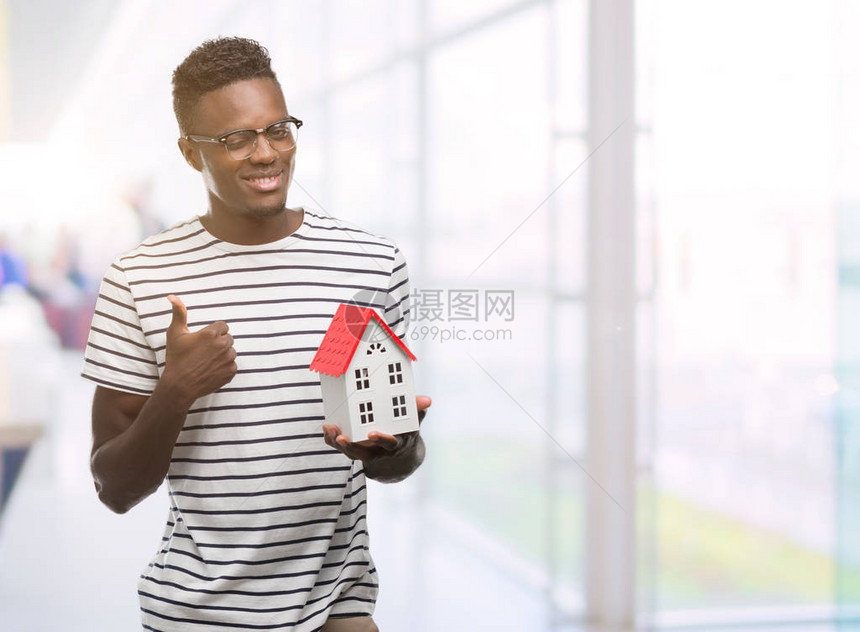 年轻的非洲裔美国人拿着房子开心地笑着做好手势图片