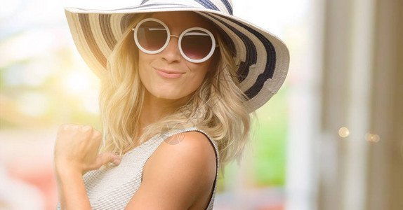 身戴太阳镜和夏帽的年轻女子骄傲兴奋和傲慢图片