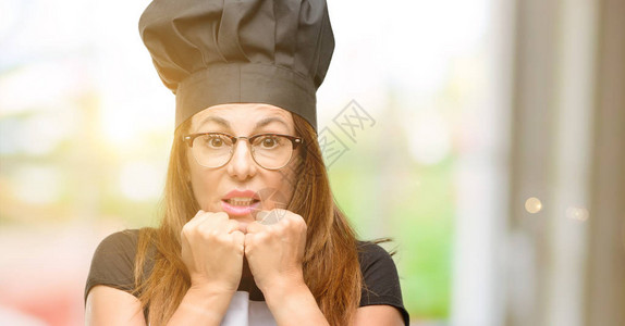 身着围裙的中年厨师女厨师感到惊吓和紧张图片