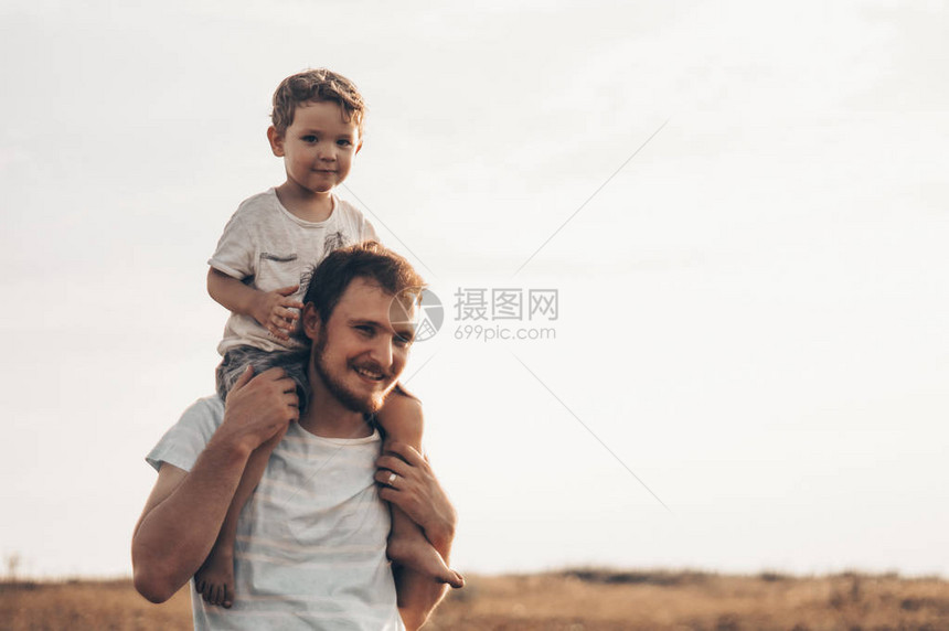 快乐的孩子和父亲一起玩爸和儿子在户外父亲背着孩子在夏天领图片
