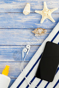 关于暑假旅行的创平板概念海滩毛巾智能手机海贝壳星尾鱼以面纸蓝木板背景和复制空间模拟板背景图片