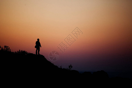 一个人站在日落的光线下岩石背景图片