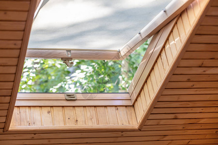 在木屋阁楼上用百叶窗或帘打开屋顶窗户图片