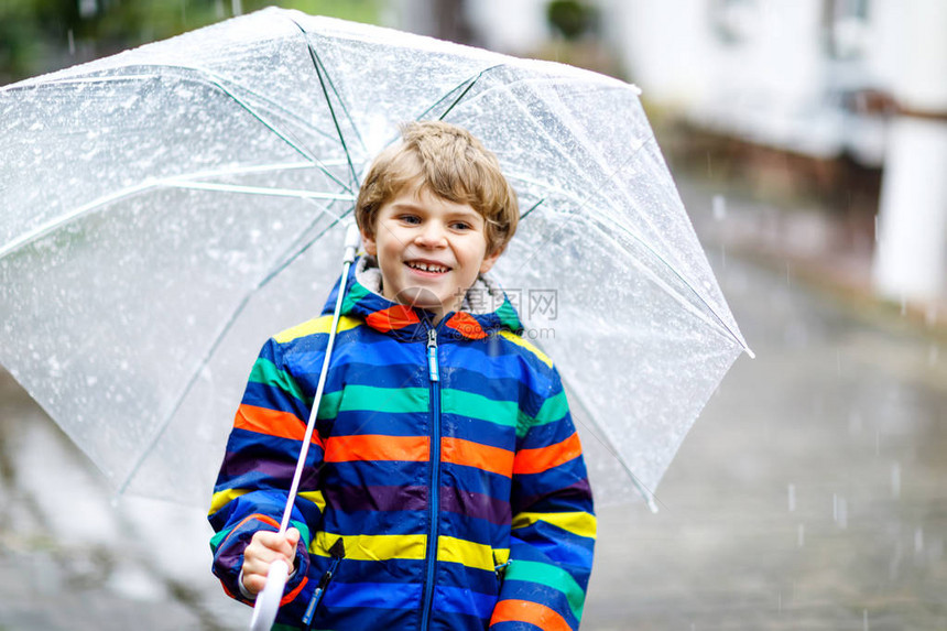 漂亮的小男孩在上学的路上在雨夹雪雨雪中行走图片